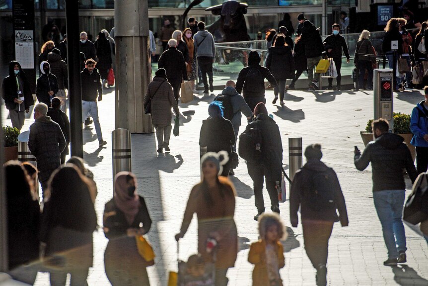 People walk through a public space on a sunny day.