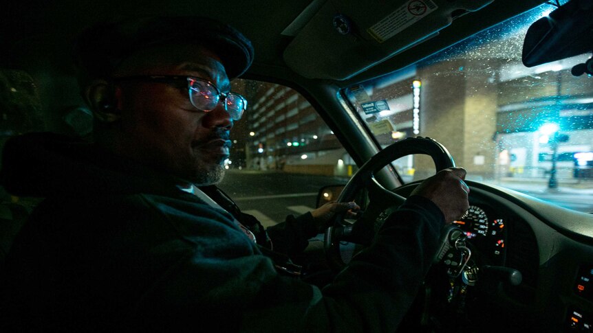 An African American man driving his car at night.