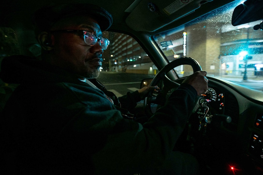 An African American man driving his car at night.