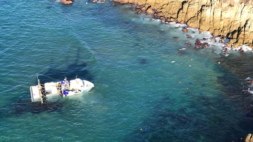 A wrecked fishing trawler and debris lie in water