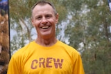 smiling man wearing yellow t-shirt with the word 'crew' across the chest