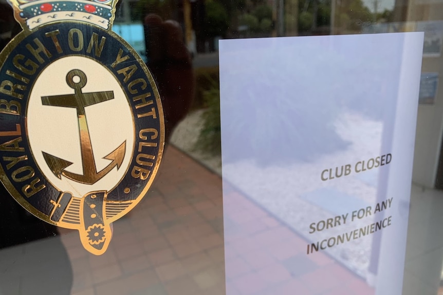 The Royal Brighton Yacht Club glass door is shut, with an A4 sheet apologising for its closure.