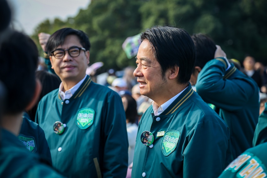 Lai Ching-te wears a green varsity jacket with KMT branding, smiling in a crowd of people
