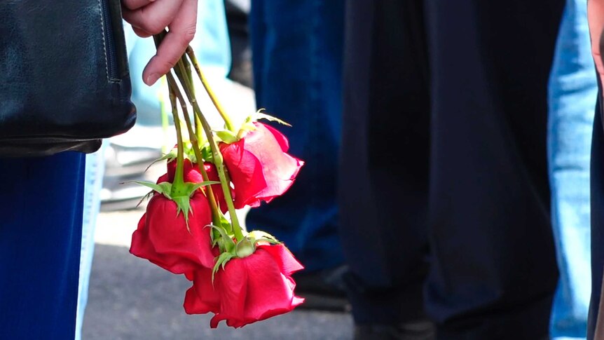 A woman holds several red roses