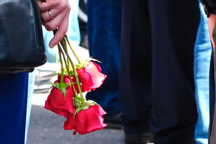 A woman holds several red roses
