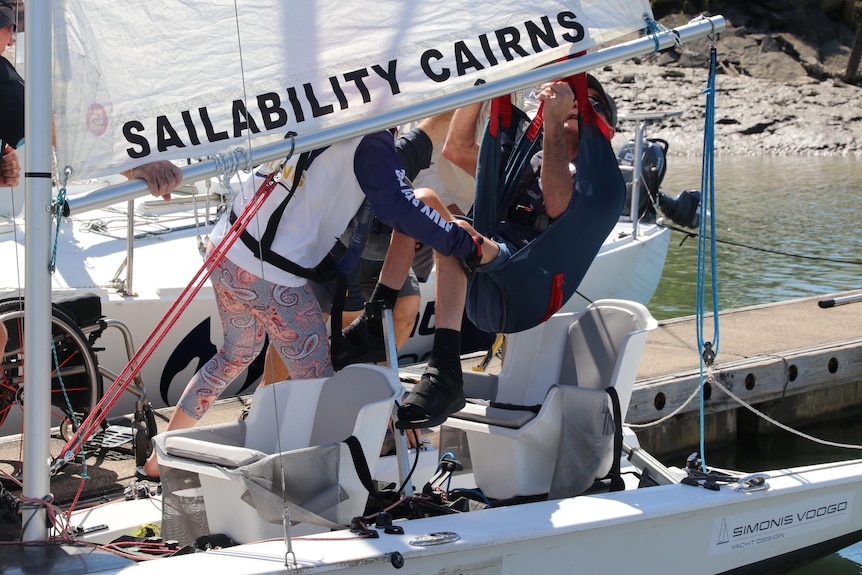 Man in sling being lifted into boat