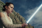 Rey with a lightsaber in the trailer for Star Wars: The Last Jedi