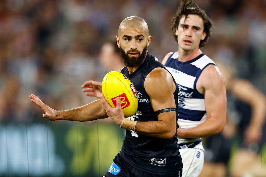 Adam Saad runs with a yellow football during Carlton's AFL match against Geelong.