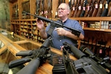A gun dealer displays several assault rifles