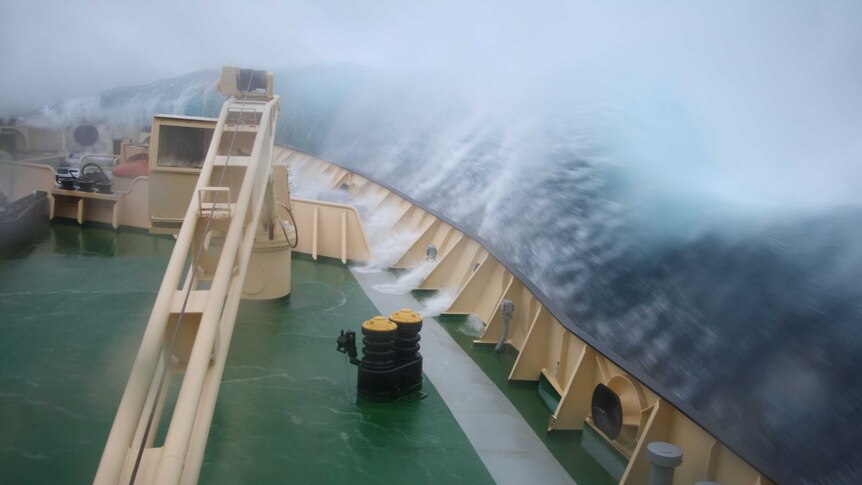 Water crashes over the side of a ship in rough seas