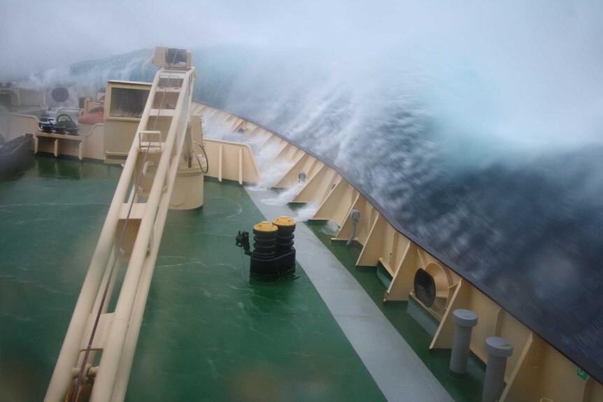Water crashes over the side of a ship in rough seas