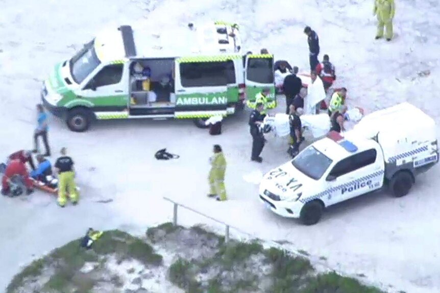 An aerial shot of a police car and ambulance with emergency crews treating people on stretchers.