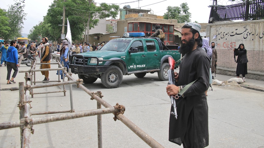 A Taliban guard standing with a gun on a street in Afghanistan.