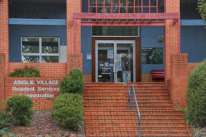 The front of a brick building with a sign saying "Ainslie Village Resident Services Administration".