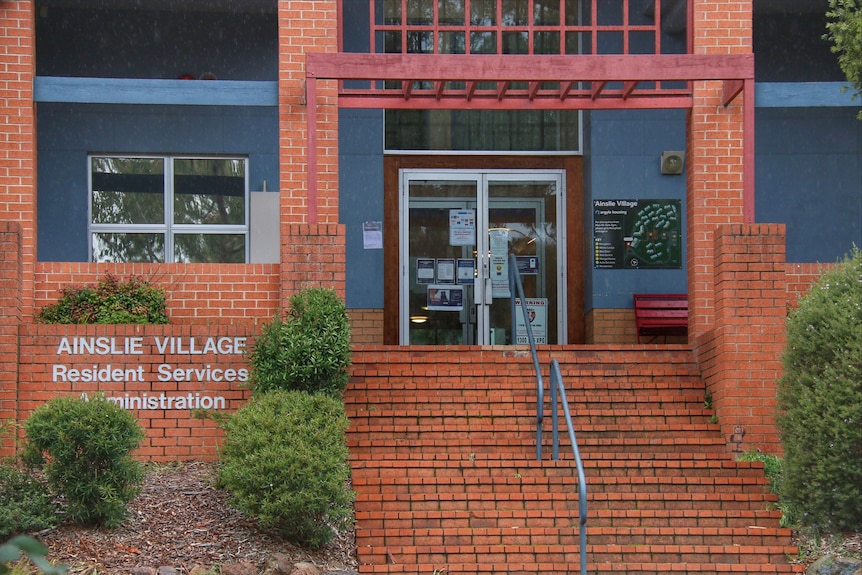 The front of a brick building with a sign saying "Ainslie Village Resident Services Administration".