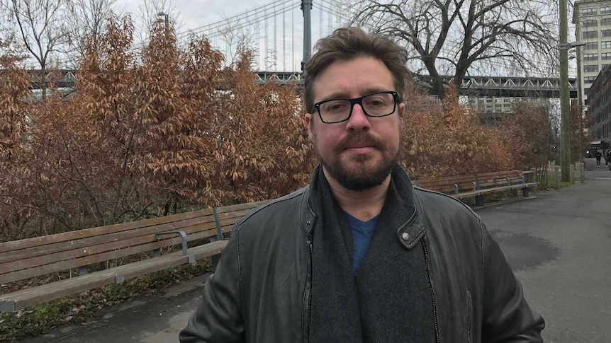 Man standing in a park with a jacket on.