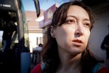 The sun hits Svitlana's face as she boards a bus to Warsaw. 