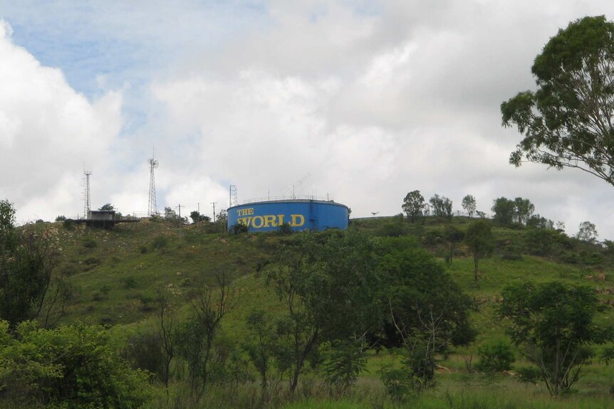 A water reservoir on top of a hill with the words The World painted on the side