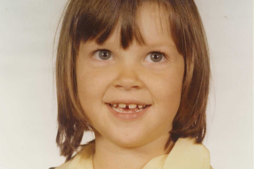 A six year old girl with a gap tooth smiles