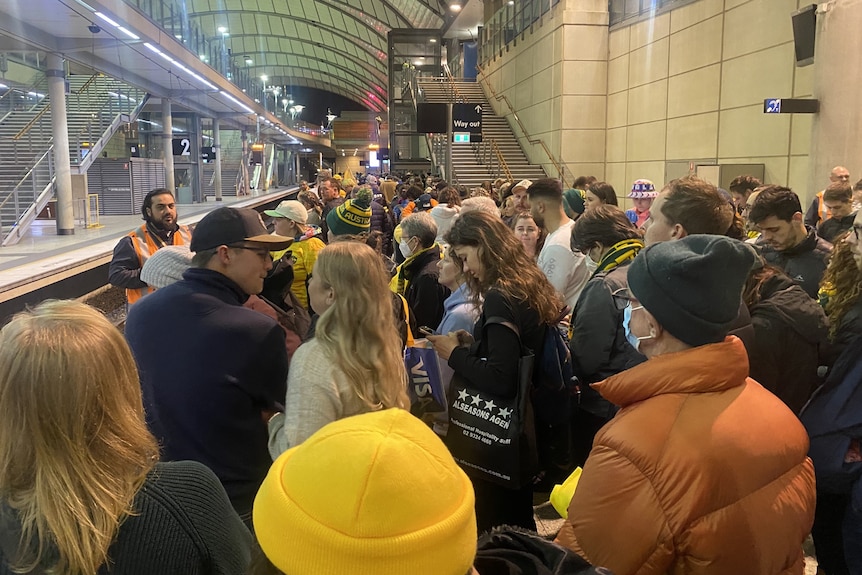 A large crowd of people waiting at a train station 