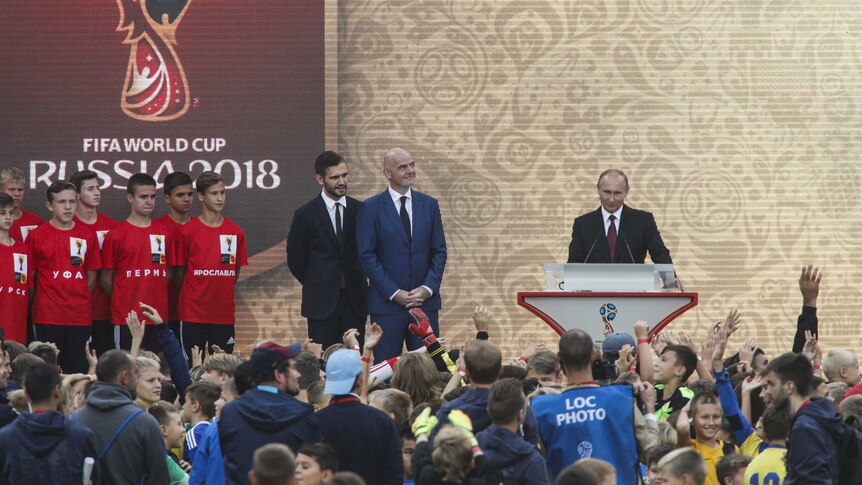 FIFA president Gianni Infantino watches on as Russian President Vladimir Putin speaks on stage.