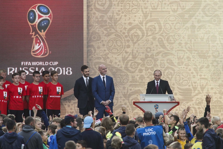 FIFA president Gianni Infantino watches on as Russian President Vladimir Putin speaks on stage.