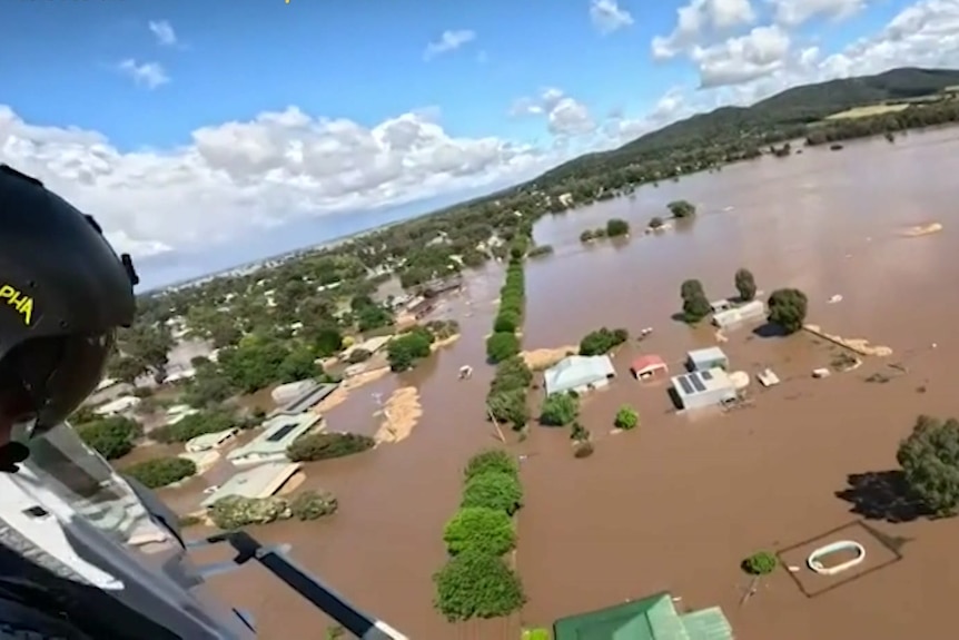 Aircraft footage of houses and trees submerged in brown floodwater