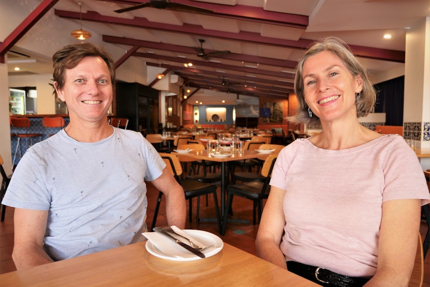 Man and woman smiling sitting at a restaurant table after-hours.