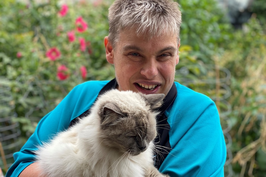 A lady smiling with a cat in a garden