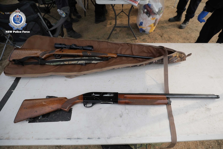 Two guns are displayed on a tressle table.