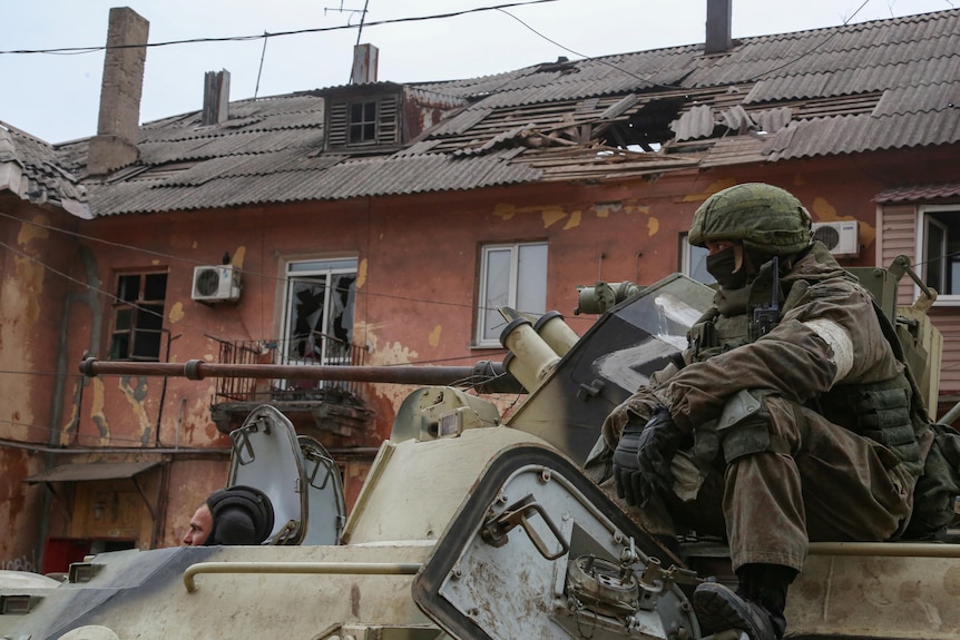 Service members of pro-Russian troops drive an armoured vehicle