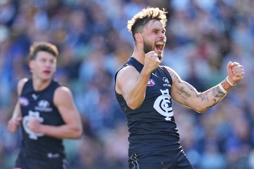 A Carlton AFL player pumps both his fists as he celebrates kicking a goal against Hawthorn.