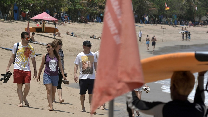 Tourists in beach wear stroll along Kuta Beach