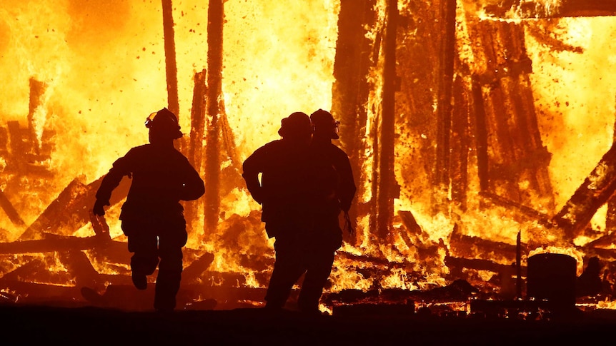 Firefighters are silhouetted running into the flames at Burning Man.