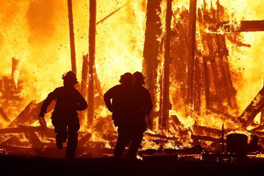 Firefighters are silhouetted running into the flames at Burning Man.