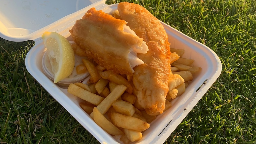 A takeaway box containing fish and chips.