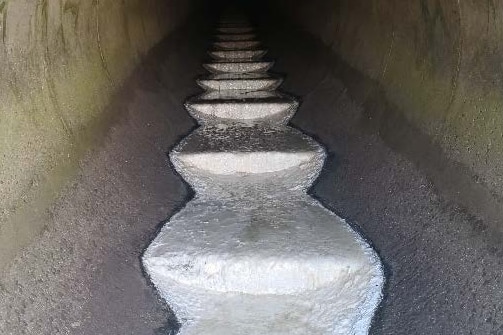 White sewage flows through a cement tunnel.