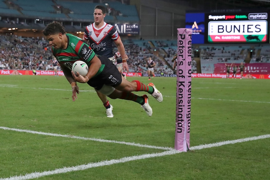 A rugby league player dives over to score a try 