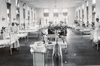 A black-and-white photograph of the Fairfield Infectious Diseases Hospital ward with patients and nurses present.