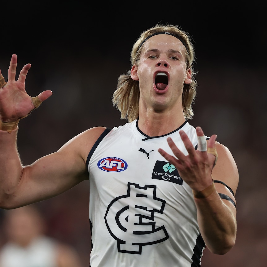 A Carlton AFL forward roars in celebration with his fingers clenched after kicking a goal in a final. 