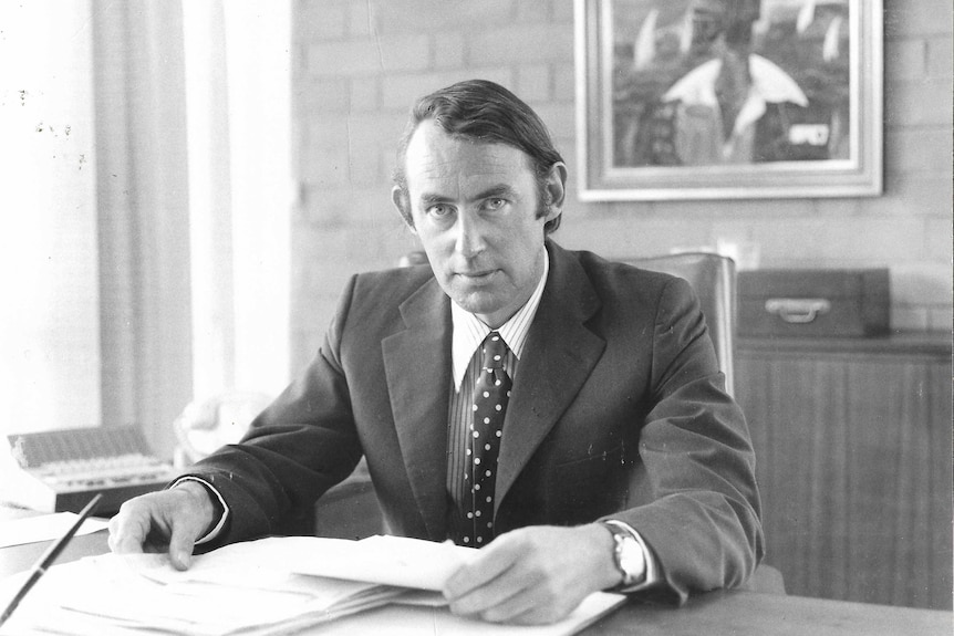 Penguin Australia's former managing director sitting at a desk in an office holding papers in his hands