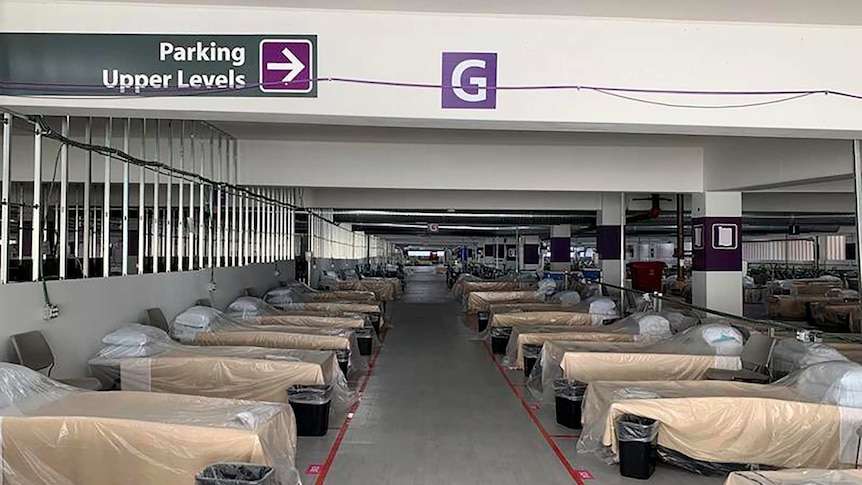 hospital beds covered in plastic sit in a parking garage