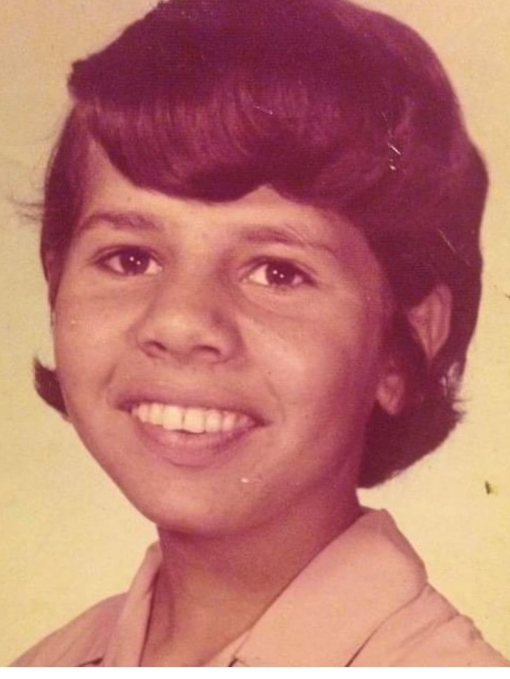 A portrait of an Aboriginal teenage girl, smiling with her hair in a short bob cut.