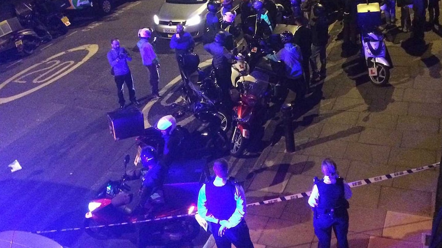 Police vehicles and emergency services at the scene of an acid attack in London.