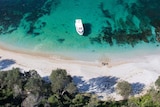 Aerial shot of a boat on blue water near a shoreline