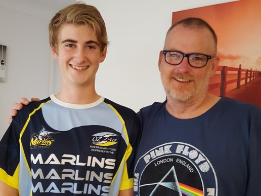 Scott and Ben Shaw stand in front of North Queensland Coyboys poster. 