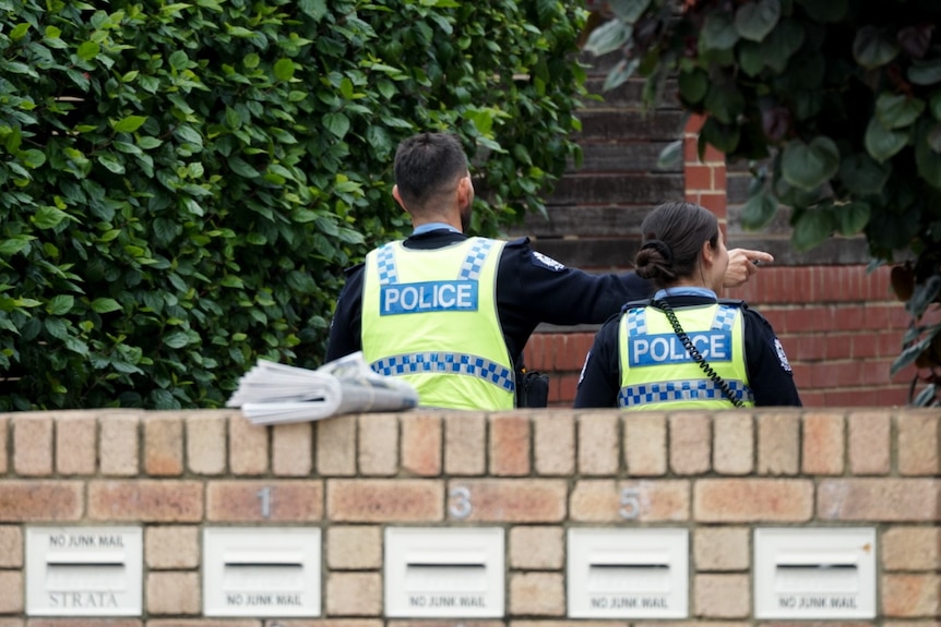 Two police officers approach a block of units to speak to residents.