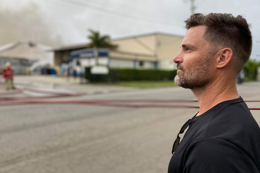 A man staring at a fire from across the road