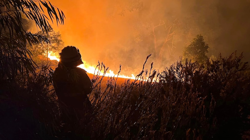 Silhouette of a firefighter with large flames in the background