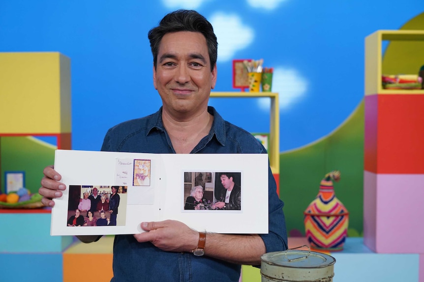 Play School presenter Alex Papps holding a scrapbook he made about his grandma to depict talking about death and grief with kids